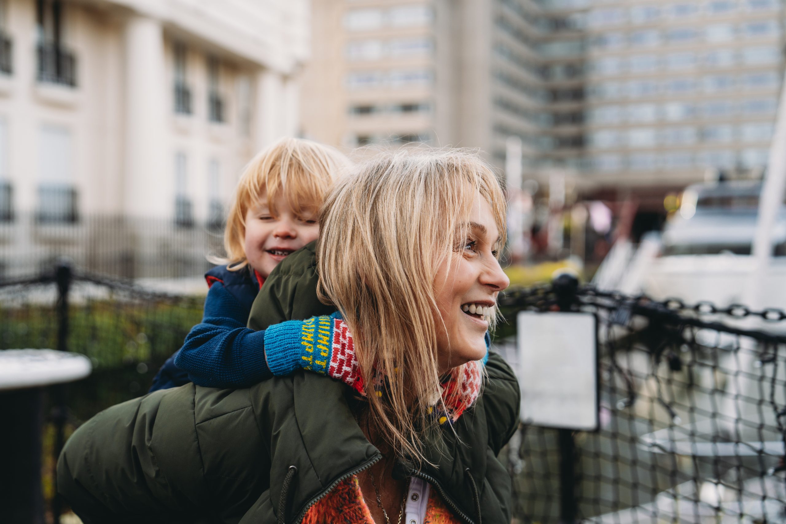 Grandmother giving piggyback ride to grandson in the city Grandmother carrying her grandson on her back, enjoying a playful moment together outdoors