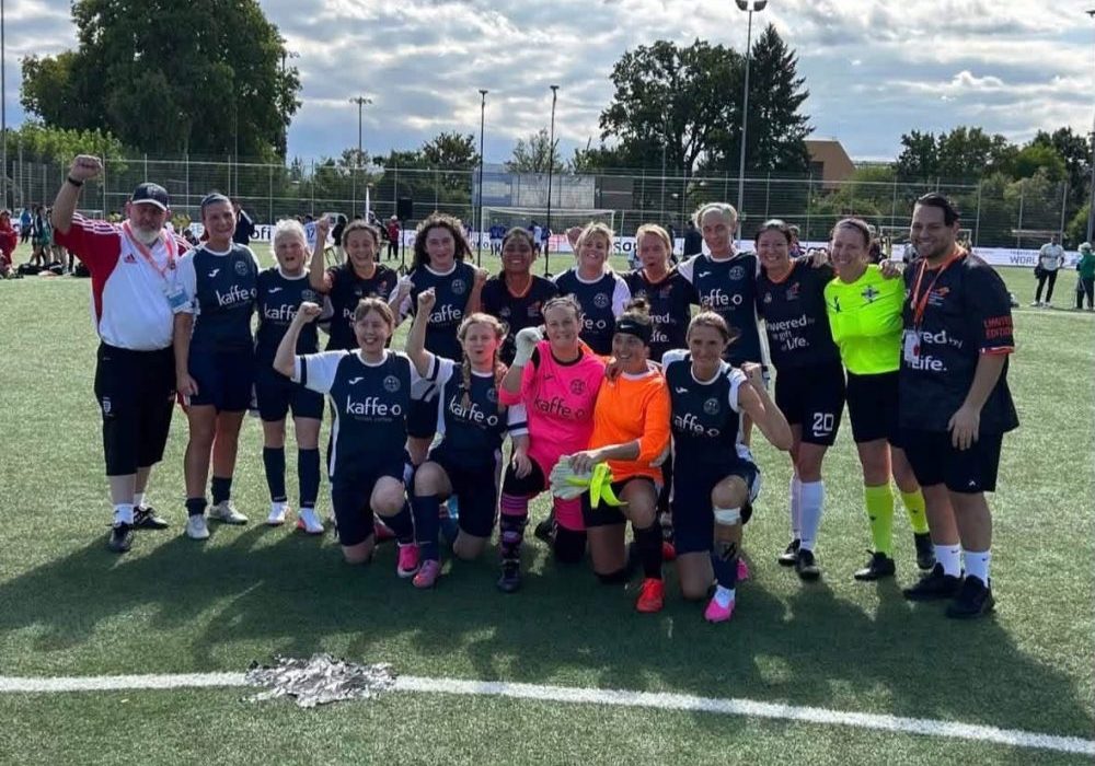 Katie Brown football team The women's football team in their kit on the football pitch. The front row are kneeling and the back row standing behind